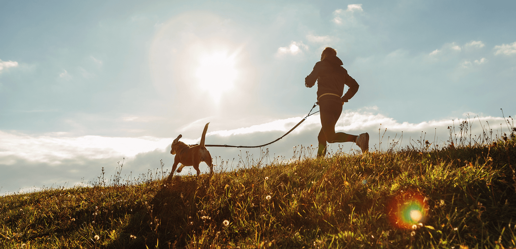 person running with a dog in a field